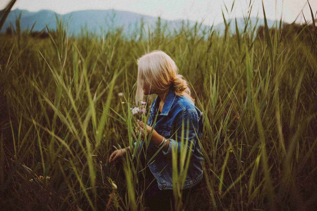 Woman picking flowers in tall grass