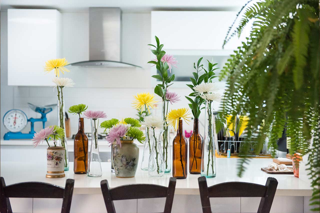 Flowers in glass bottles on kitchen counter