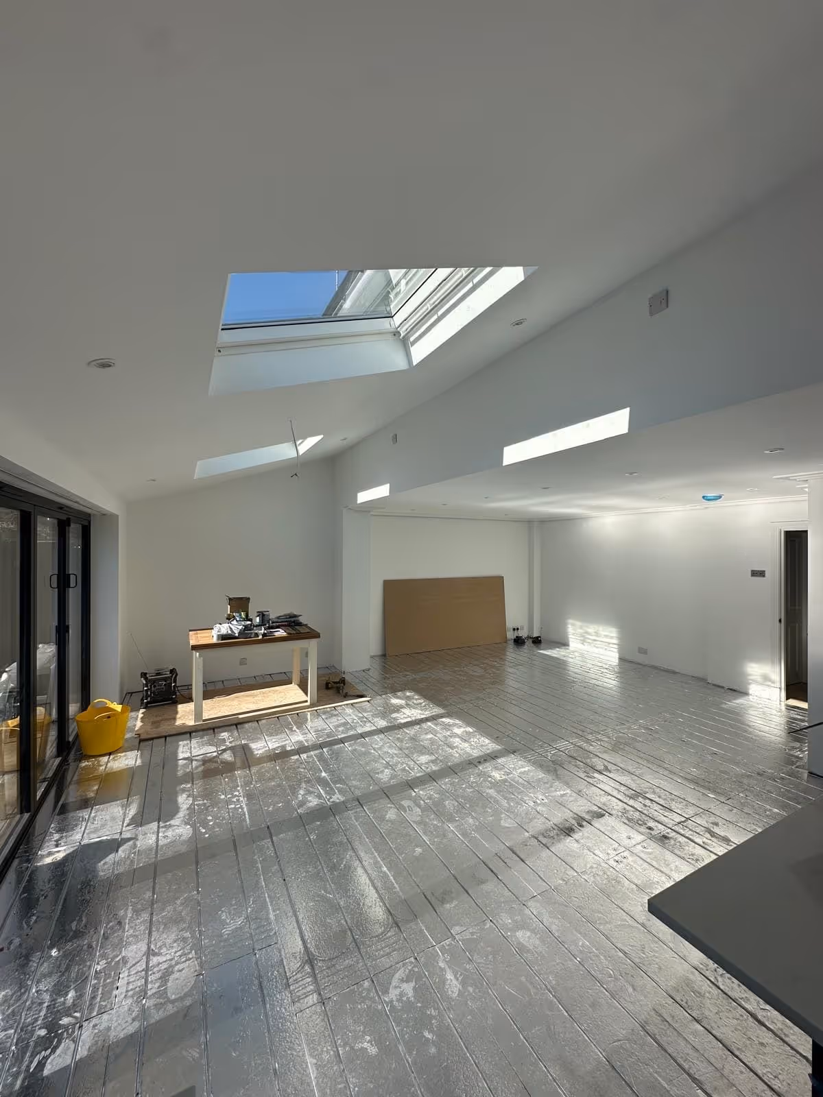 Bright unfinished room with white walls, skylights, and silver insulation on the floor.