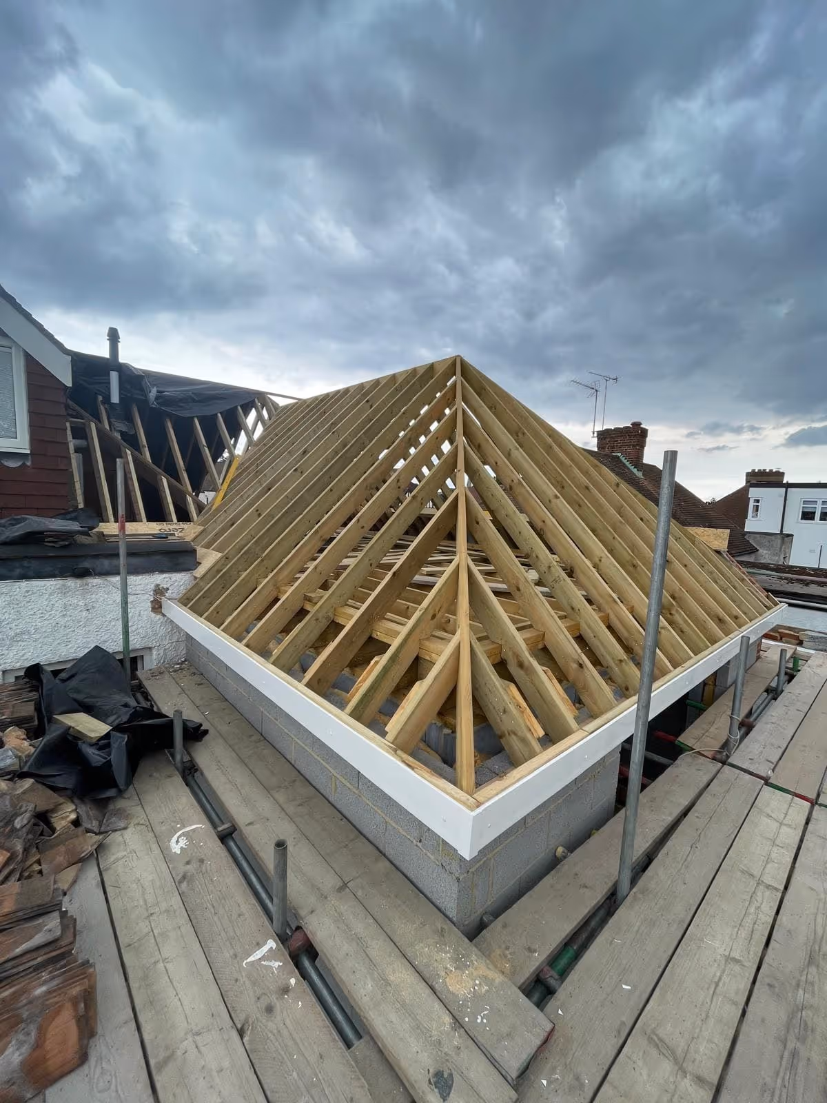 A wooden roof frame under construction on a building with cloudy sky above.
