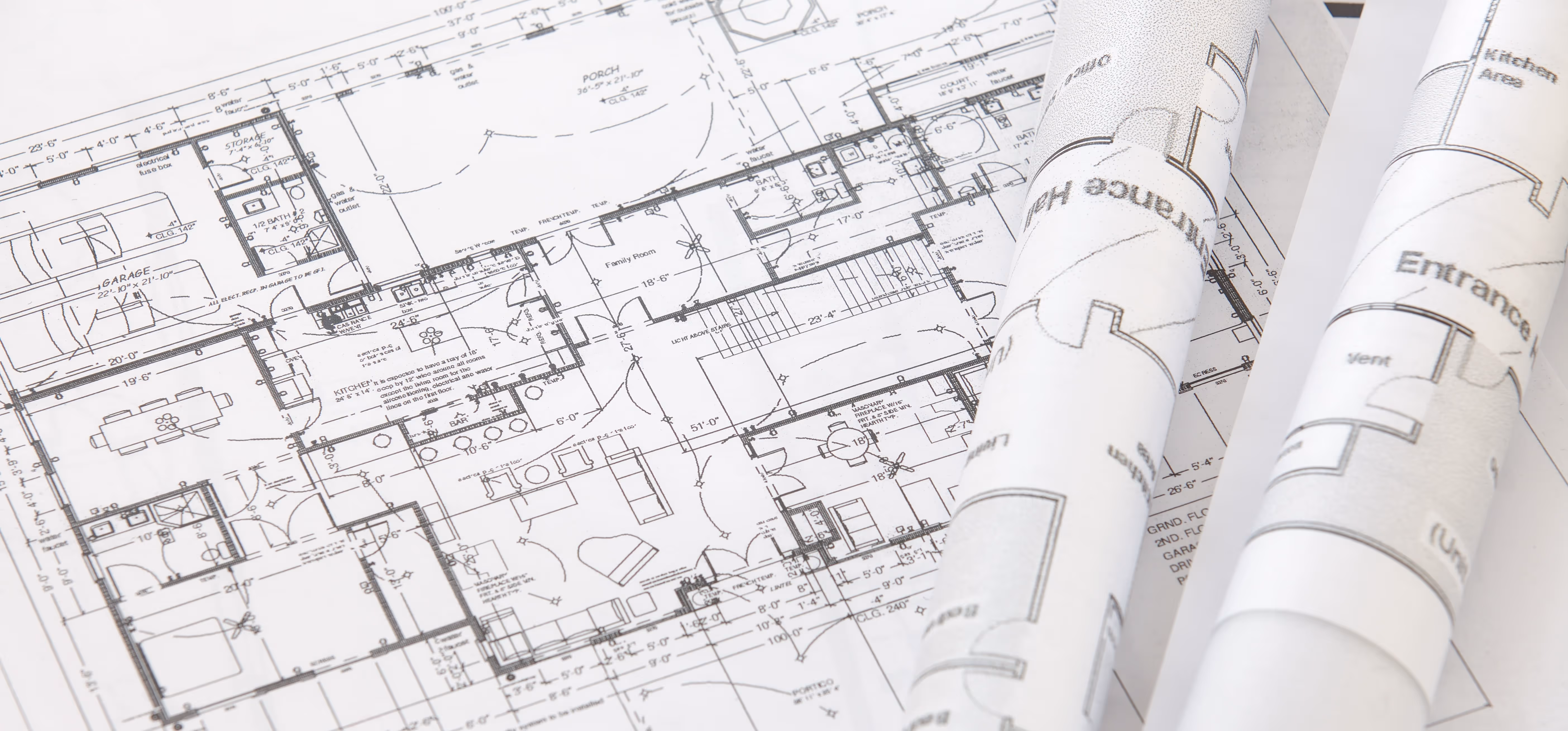 Architectural blueprints with detailed floor plans, including rooms, measurements, and annotations, alongside rolled-up plan sheets.