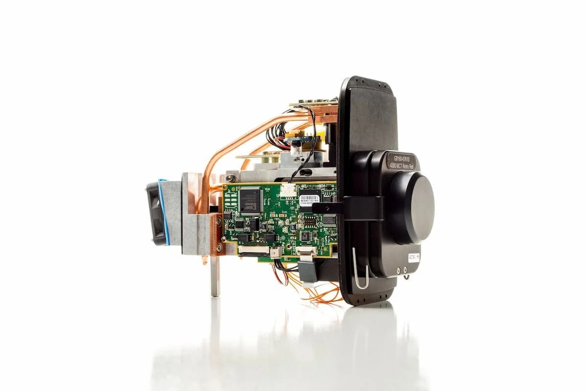 Side view of compact scientific instrumentation device featuring circuit board, copper tubing, and black casing labeled "330 MCT Retro RIA".