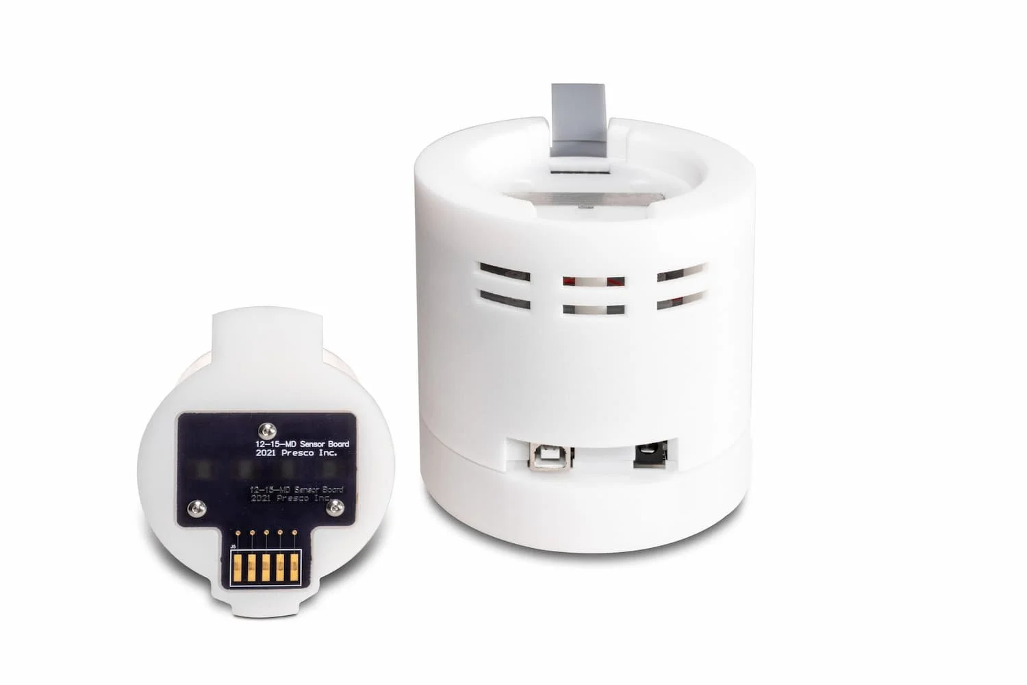 White cylindrical device with ventilation slots and a detachable round sensor board labeled '12-15-MD Sensor Board 2021 Presco Inc.'