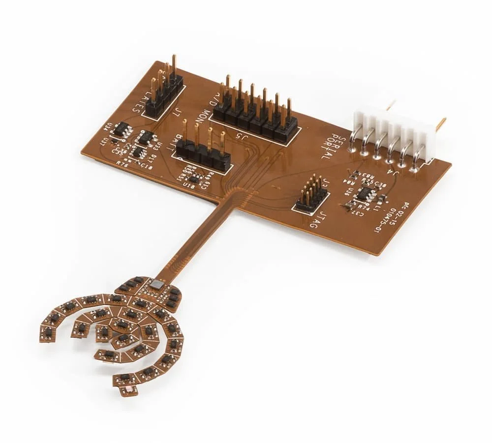 Brown flexible printed circuit board with multiple connectors and a curved LED array at one end.