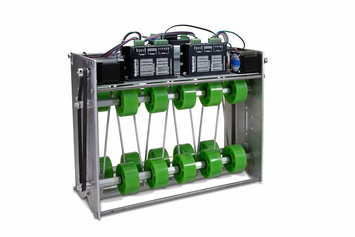 Mechanical device with green wheels connected by strings and two stepper motors with circuit boards on top.