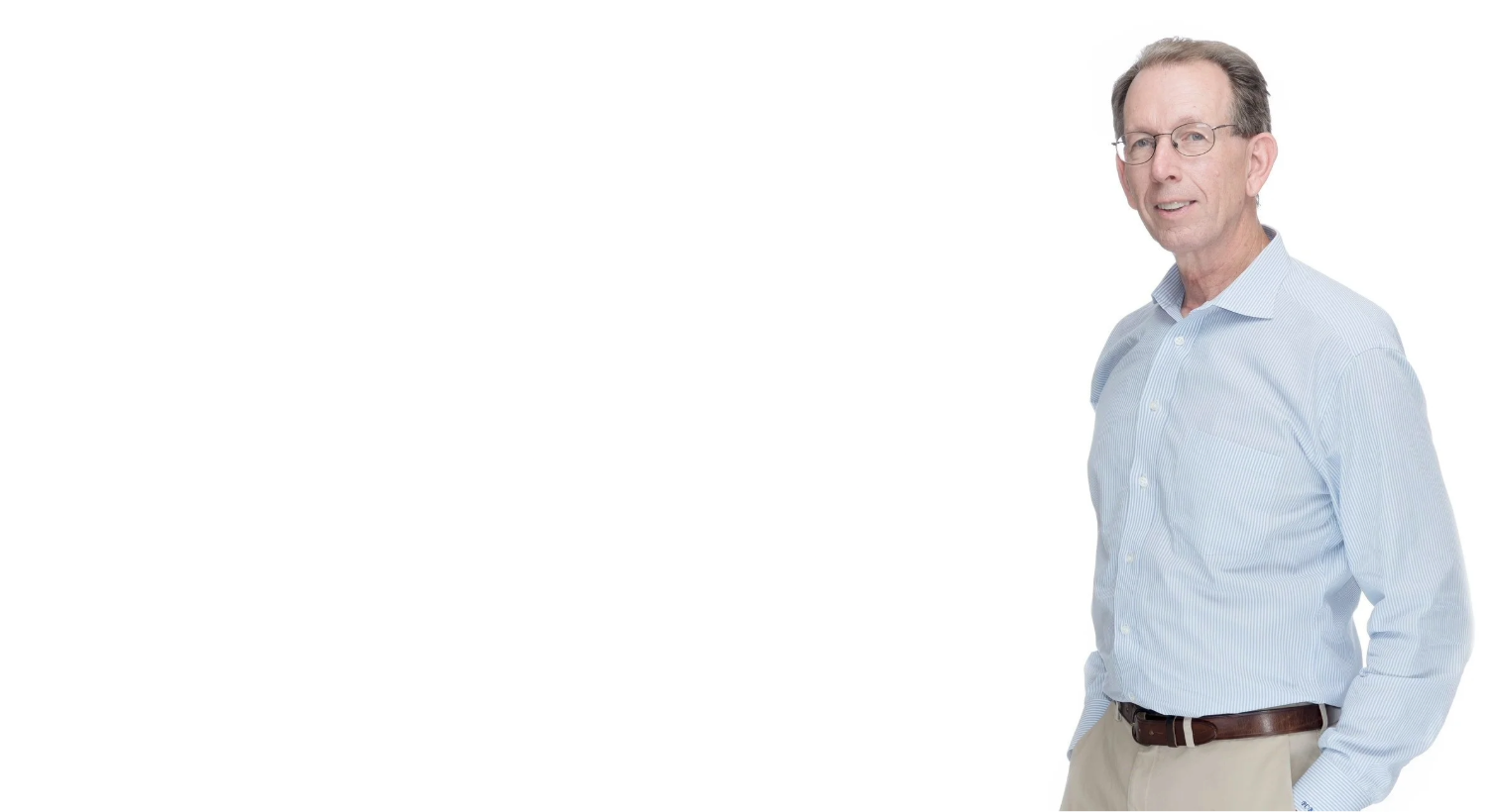 Middle-aged man wearing round glasses, light blue striped shirt, and beige pants, standing with hands in pockets against white background.