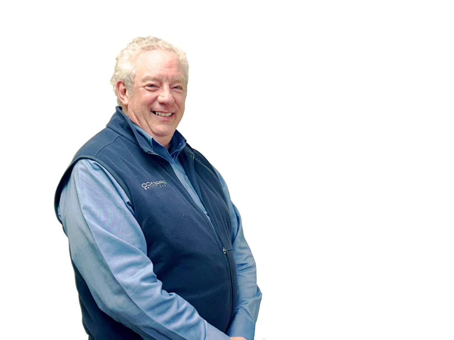 Smiling older man with curly white hair wearing a blue shirt and dark blue vest.