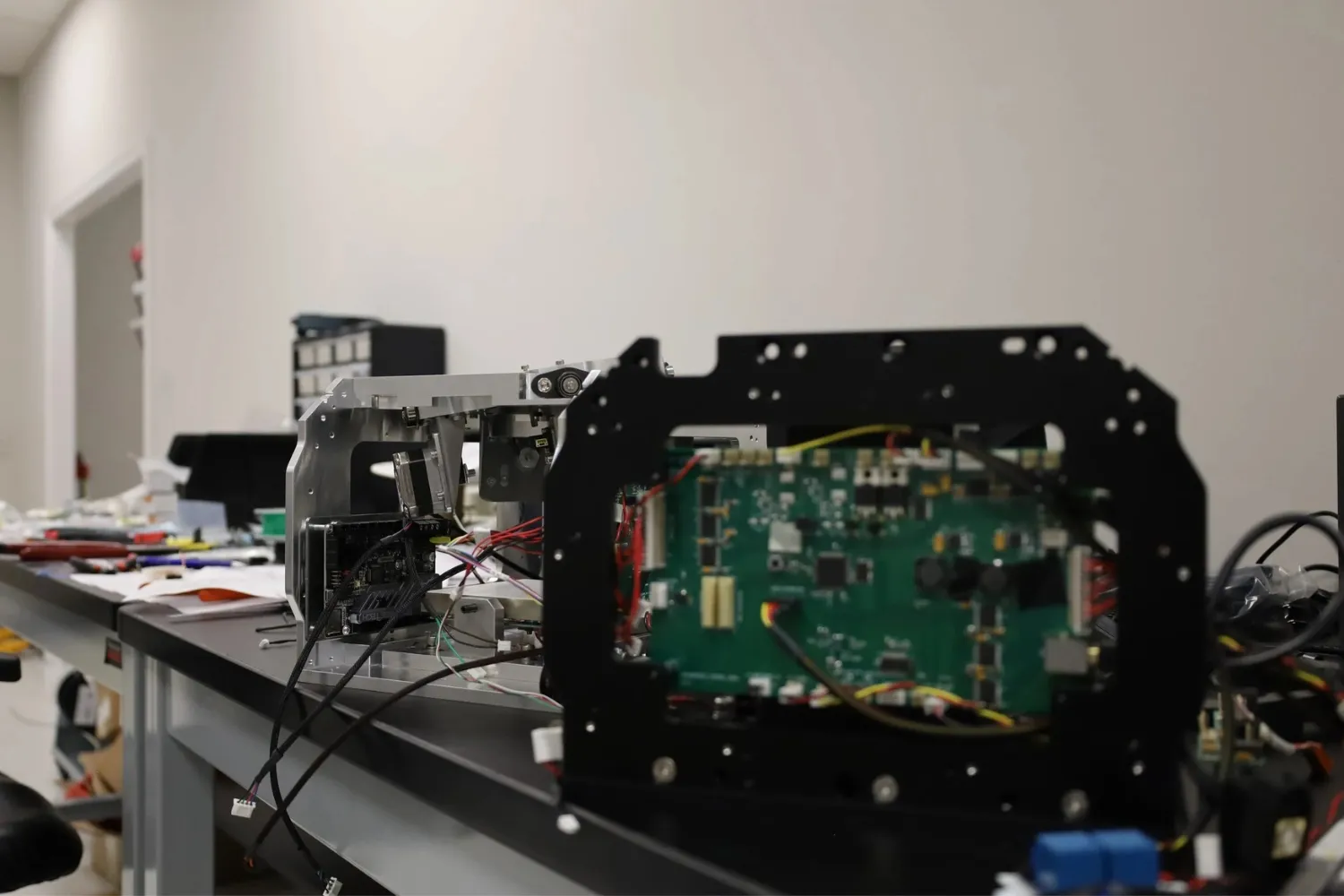 Close-up of electronic components and circuit boards mounted on a metal frame on a laboratory workbench.