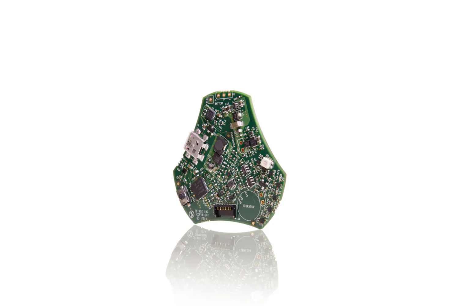 Close-up of a green printed circuit board with electronic components and connectors, reflected on a white surface.