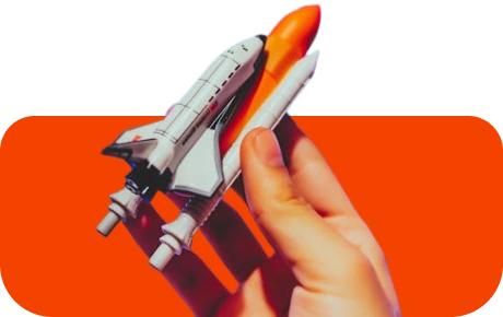 miniature rocket in hand on a red background