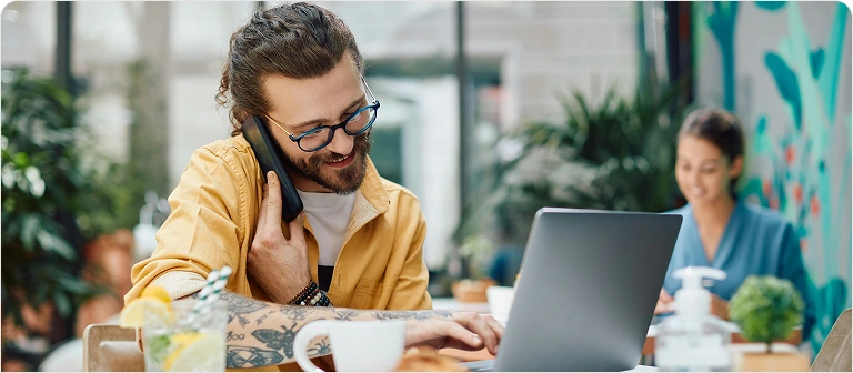 Man talking over the phone and working on a laptop