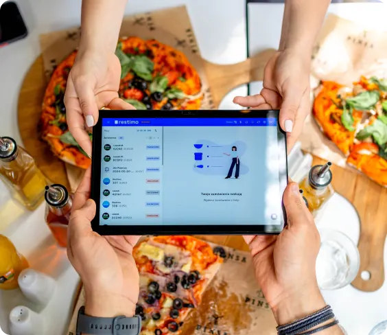 Two people holding a tablet with the Restimo order panel over pizzas