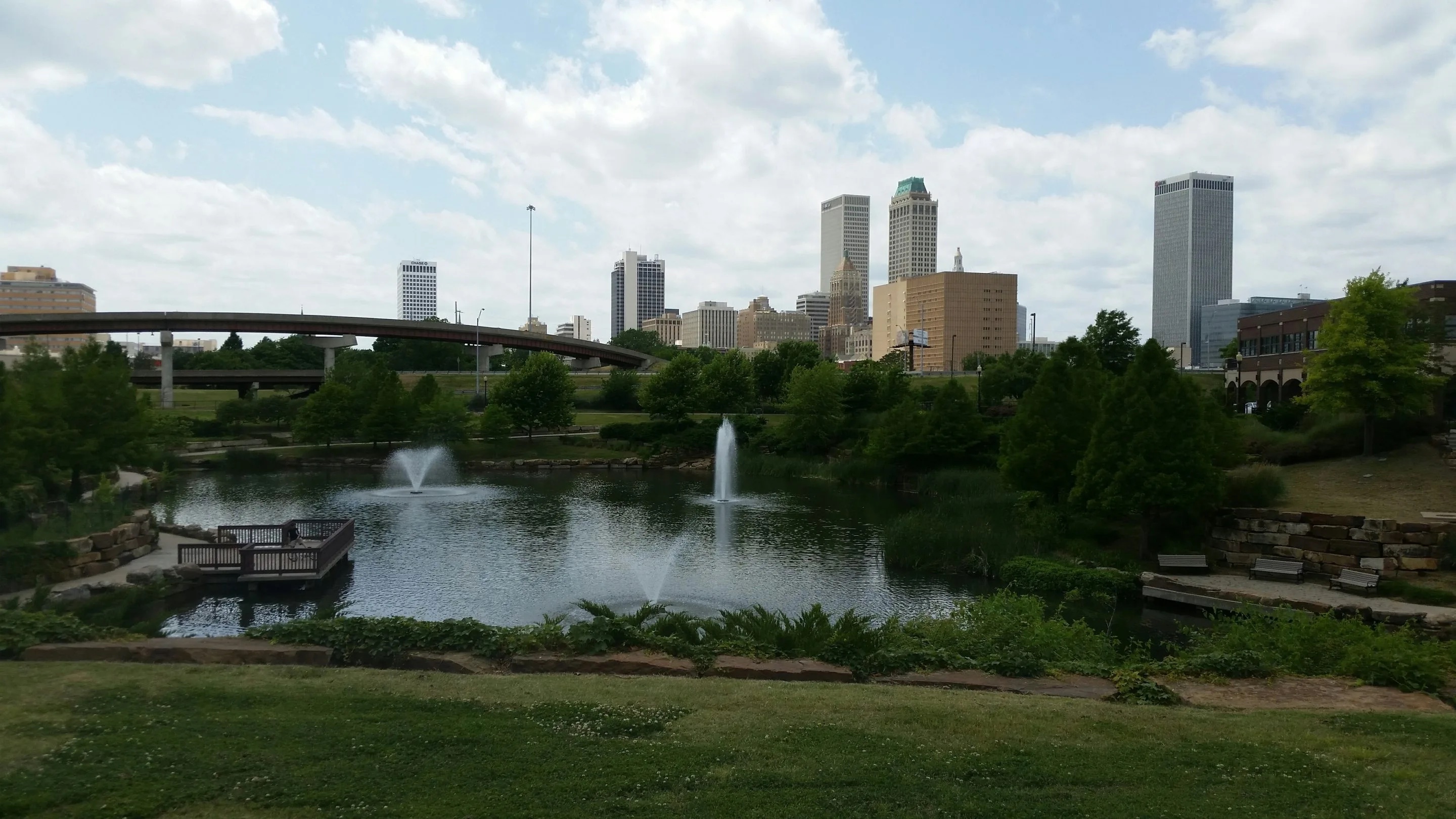 Tulsa skyline with a park, pond, and fountains in the foreground.