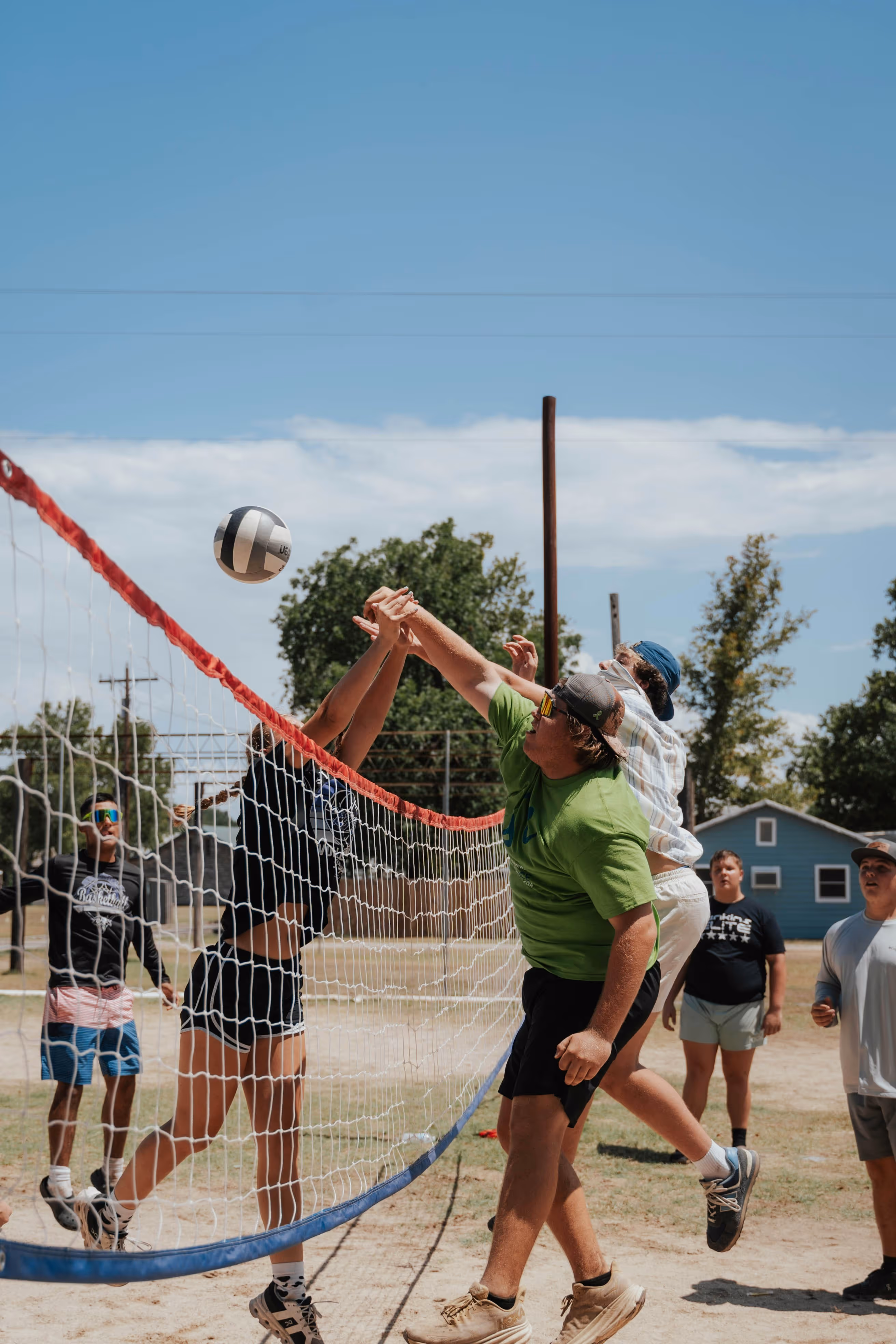 Group of people playing volleyball outdoors during a team activity in a social environment