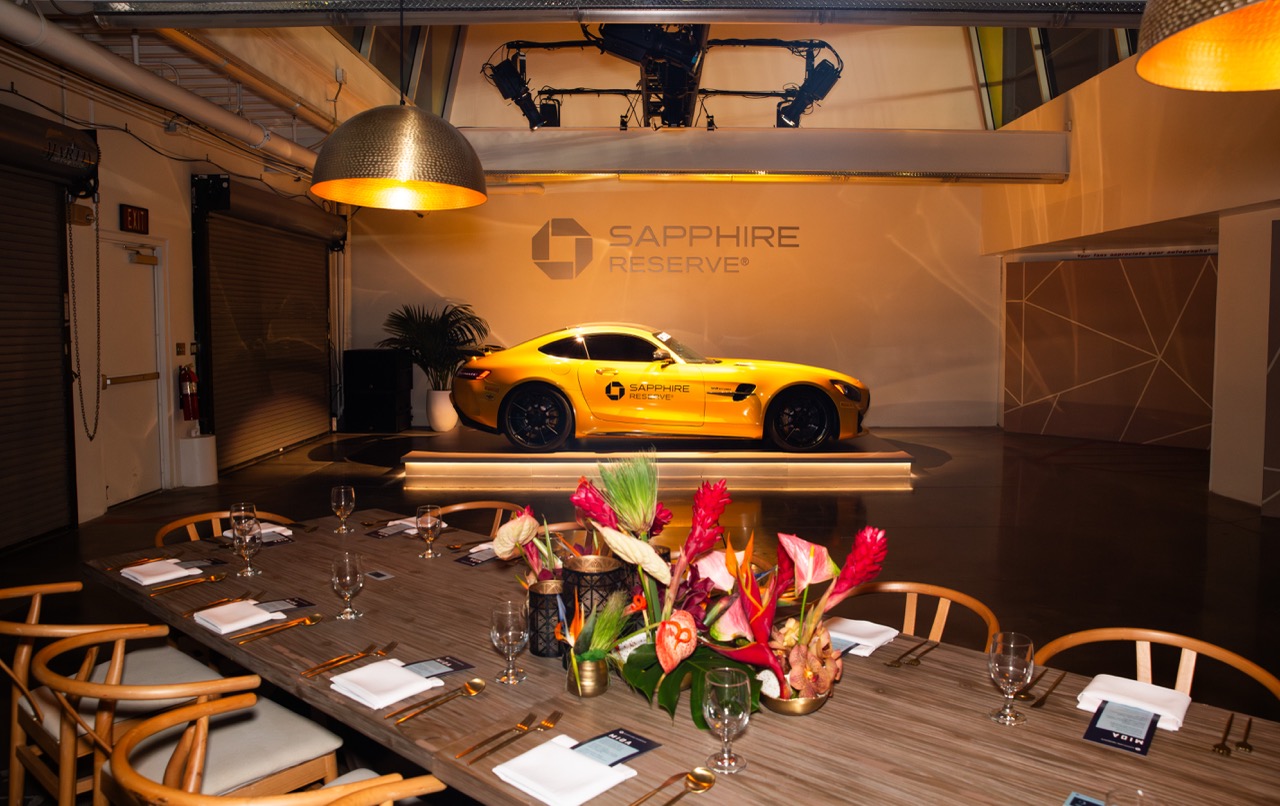Chase Sapphire dinner installation in a speedway garage for F1 in Las Vegas. featuring decorative flowers and a yellow sports car 