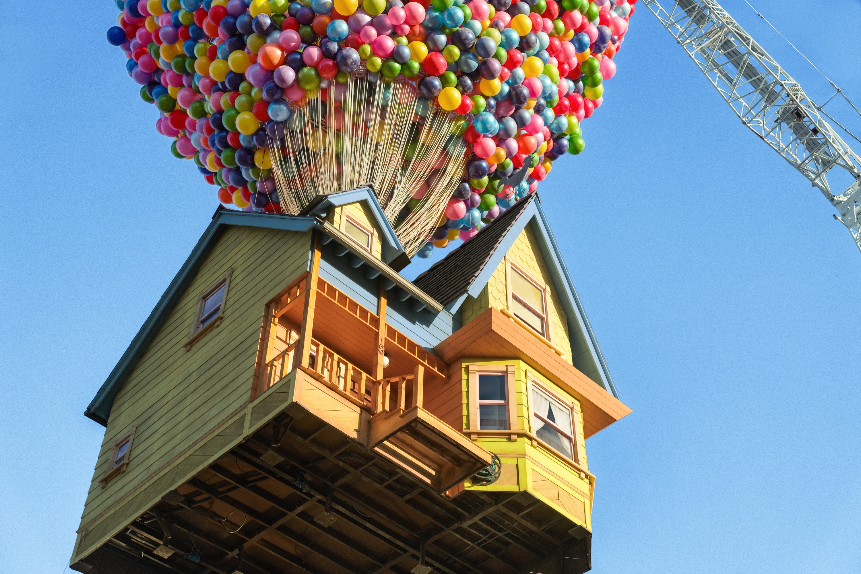 A full scale recreation of the house from the film UP. It features brightly colored siding and trim, and thousands of balloons. The entire structure is being lifted by a massive crane.