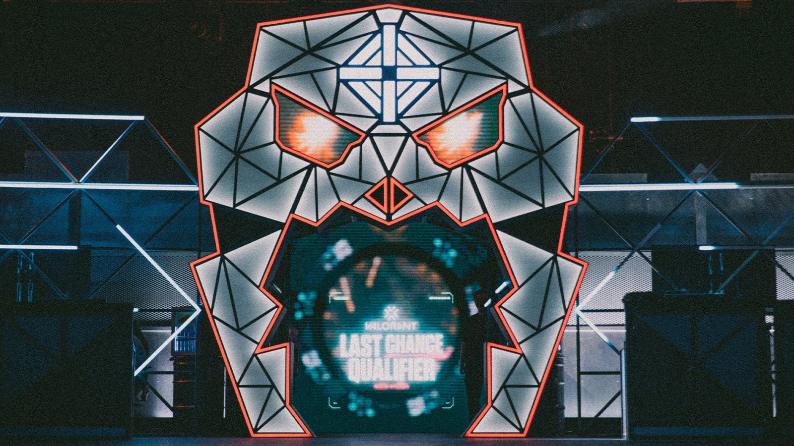 Glowing geometric skull arch with red eyes framing a screen showing Valorant Last Chance Qualifier for Riot Games