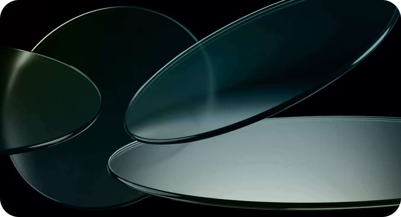 Close-up view of overlapping transparent circular glass plates with a dark greenish tint on a black background.