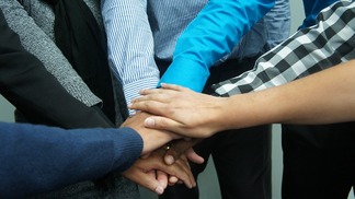 Several people placing their hands together in a teamwork gesture.