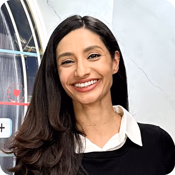 Smiling woman with long dark hair wearing a white collared shirt under a black sweater.