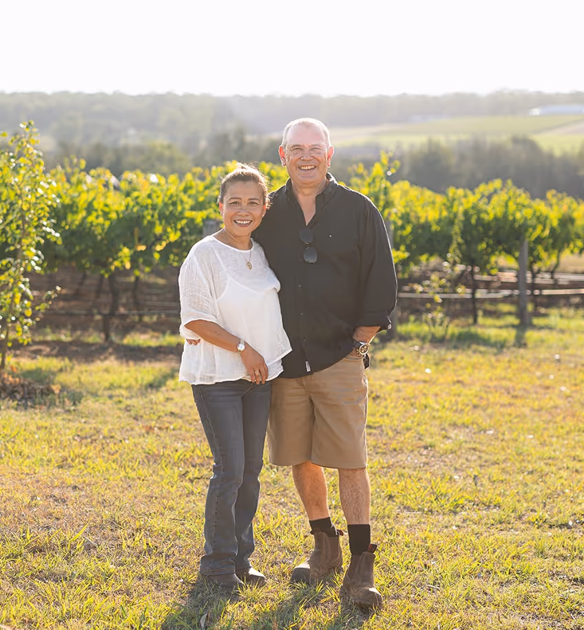 Owners of Red Door Collective, Evelyn and Steward, posing in front of the vineyard.