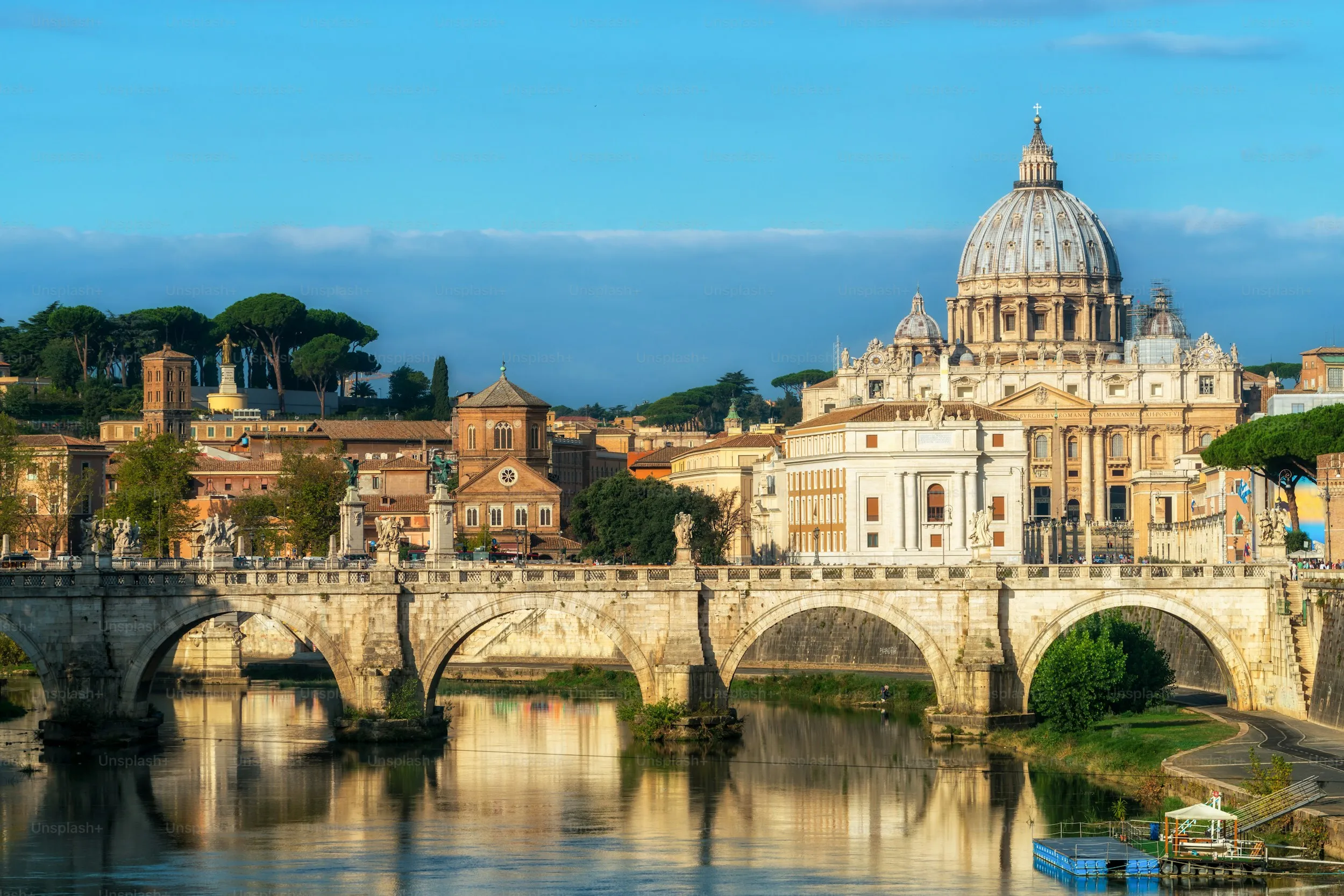 View of the Saint Peter's Basilica dome and a stone bridge over the Tiber River in Rome.