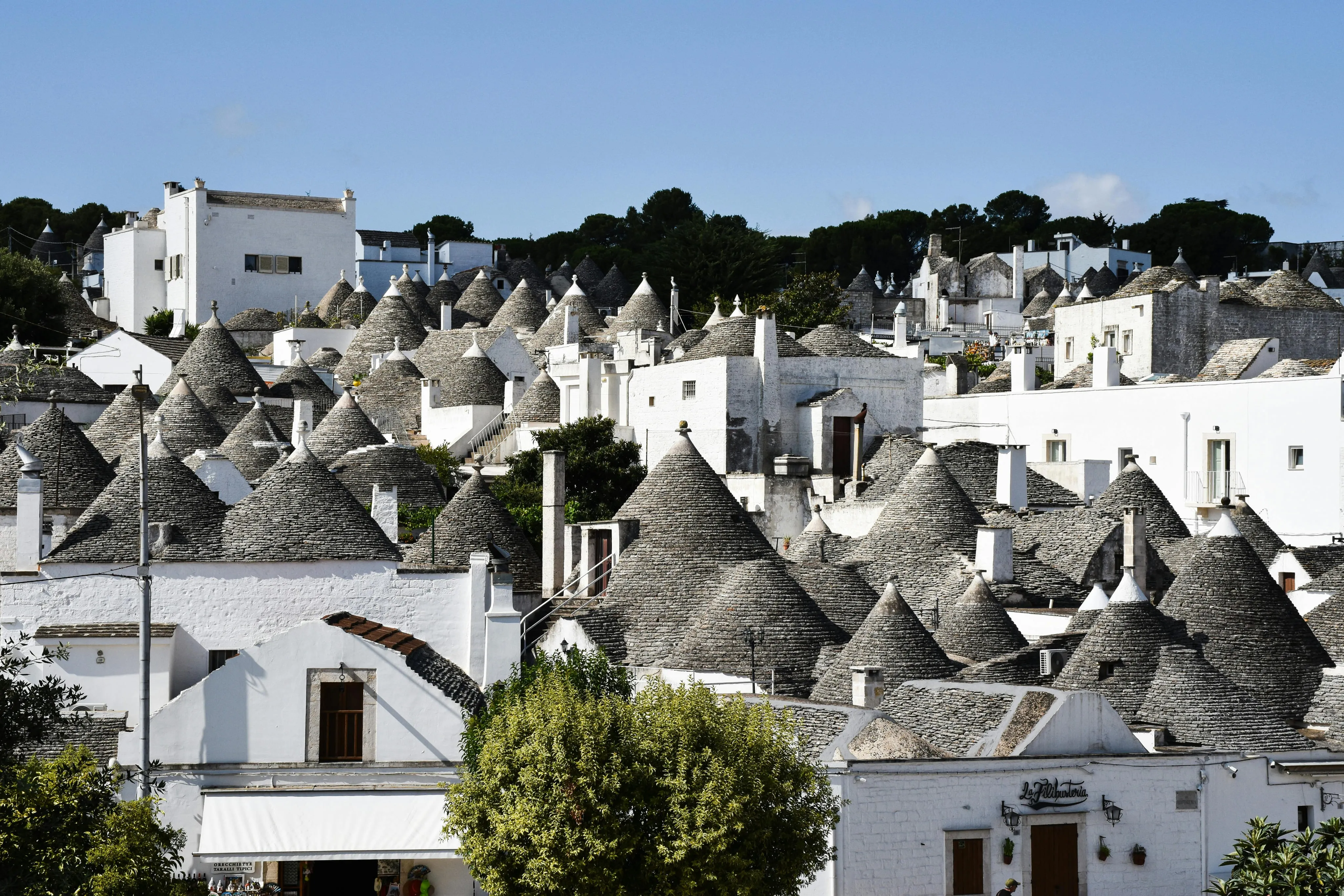 Cluster of traditional white houses with conical stone roofs in Alberobello, Italy.