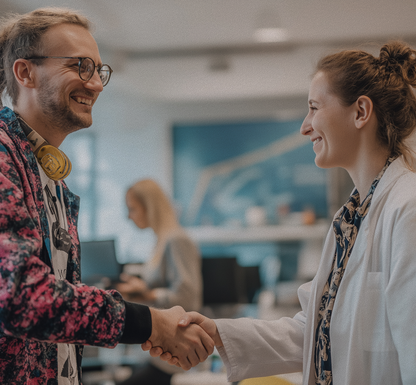 Smiling man and woman shaking hands in an office setting.