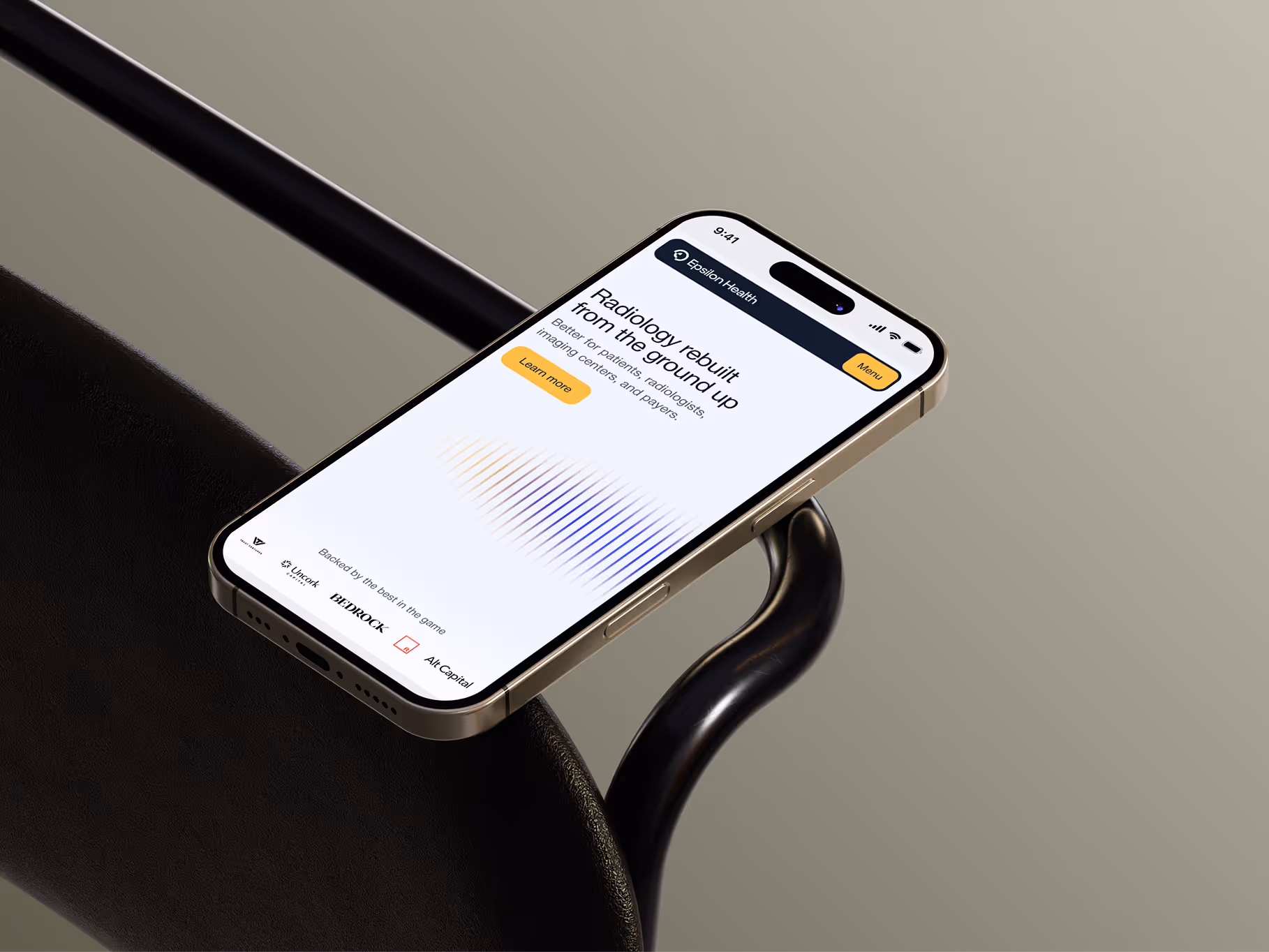 Smartphone displaying a Radiology website with an orange header and a Learn more button, resting on a black chair armrest.