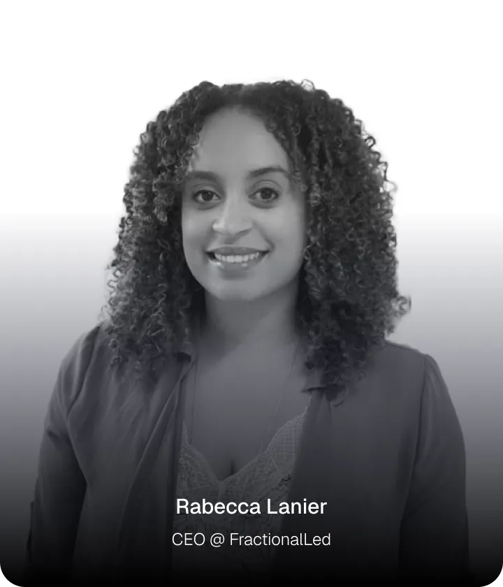 Portrait of a smiling woman with curly hair wearing a blazer and lace top.
