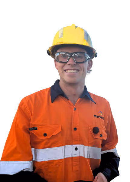 Smiling worker wearing safety glasses, a yellow hard hat, and a high-visibility orange Marlanda shirt with reflective stripes.