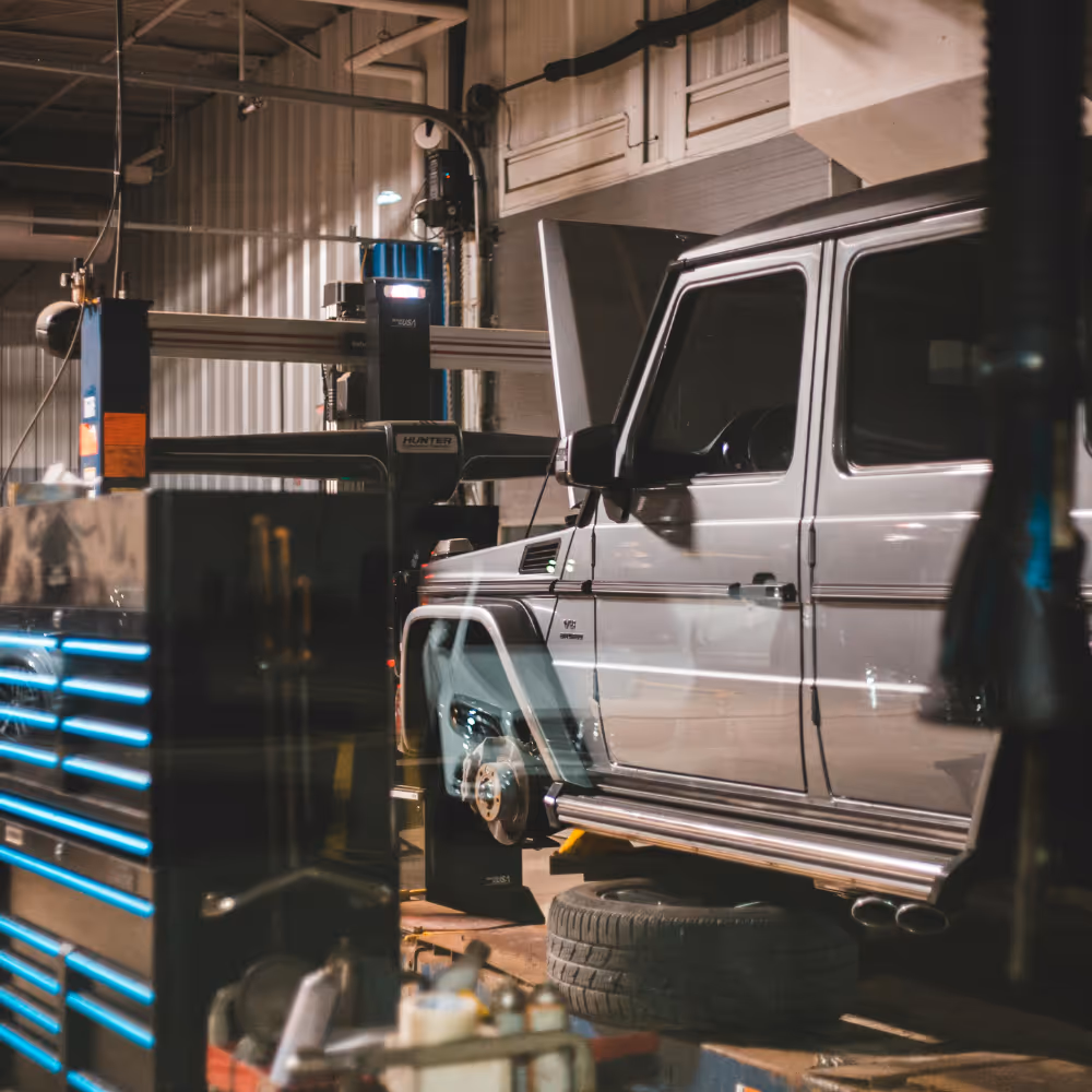 Gray SUV with removed front wheel elevated in an automotive repair shop.