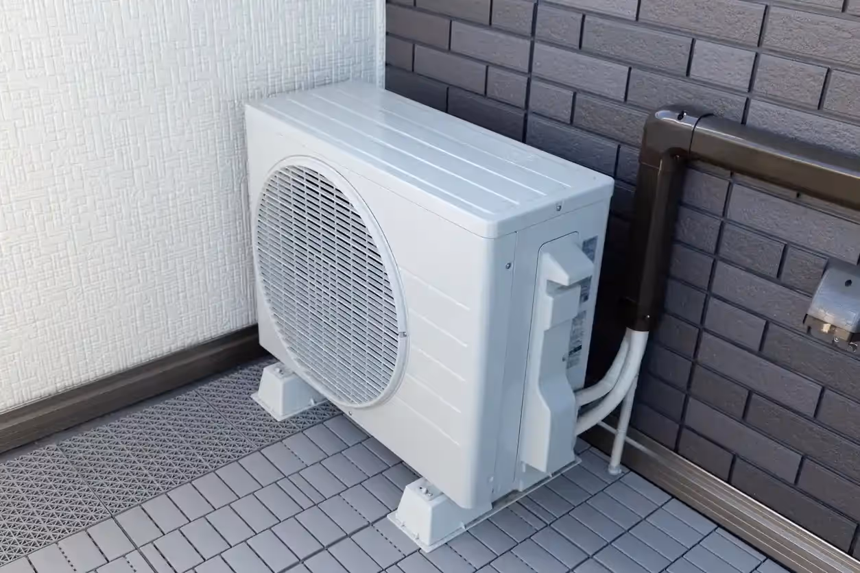 A single mini-split air conditioning unit placed on the ground next to a building.