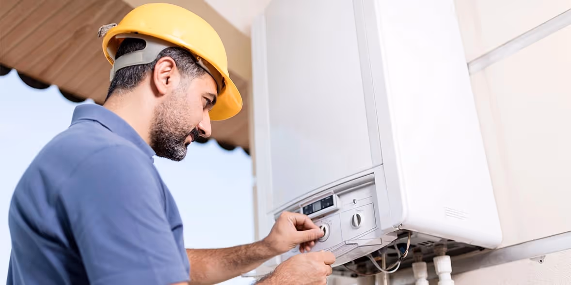 Man servicing wall-mounted combination boiler unit.