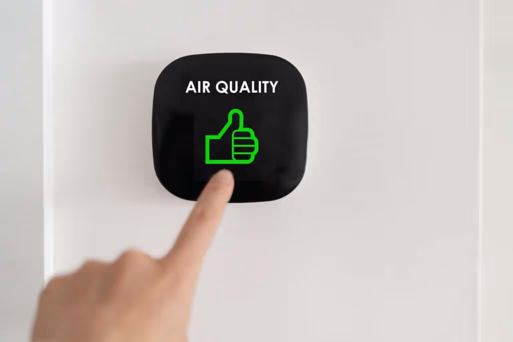 Hand touching indoor air quality monitor.