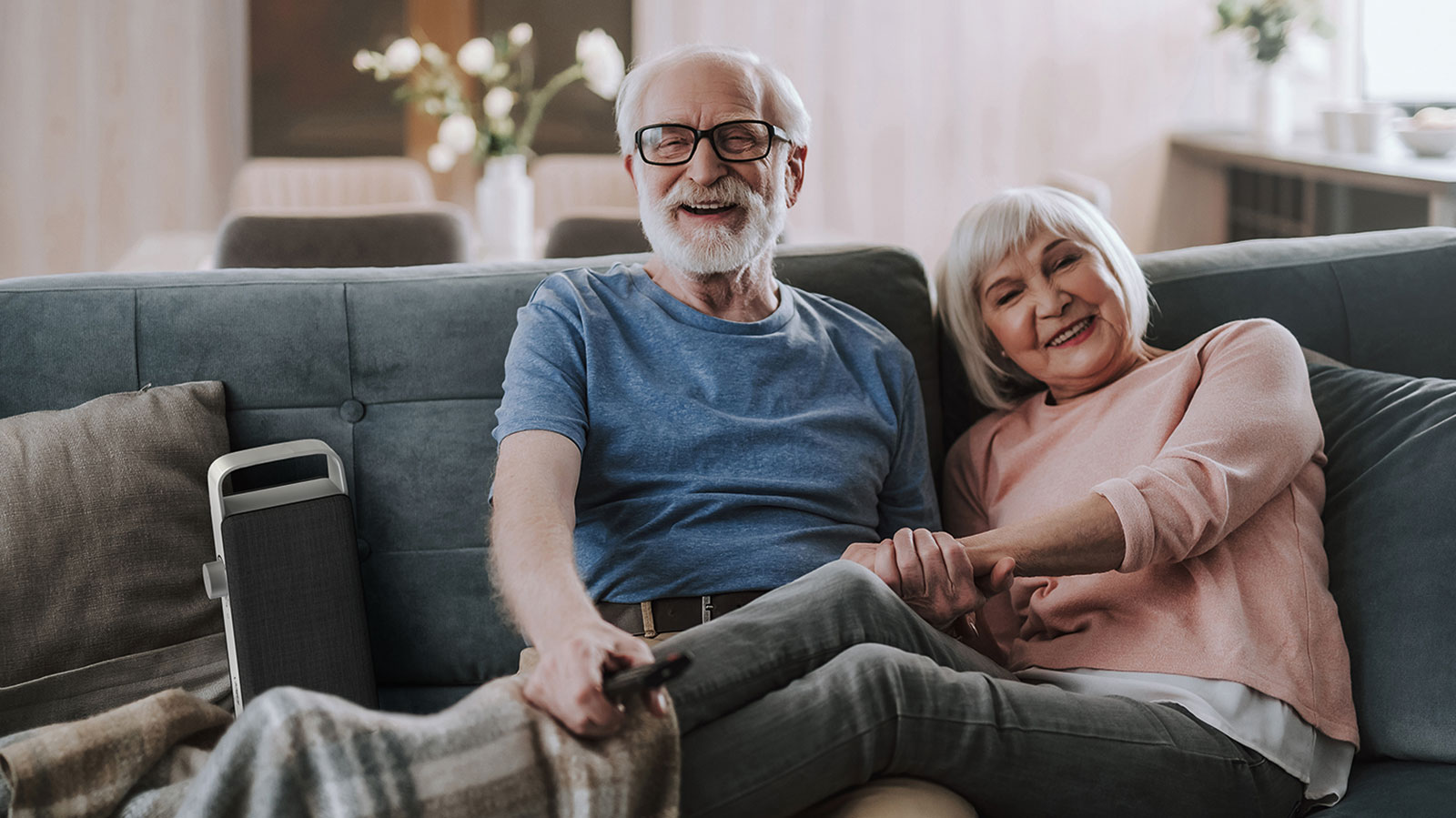 Zwei Personen sitzen auf einem Sofa, neben ihnen steht ein tragbarer Faller Lautsprecher