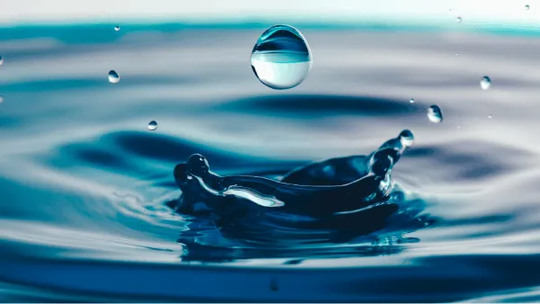 Blue water droplet landing on a body of water