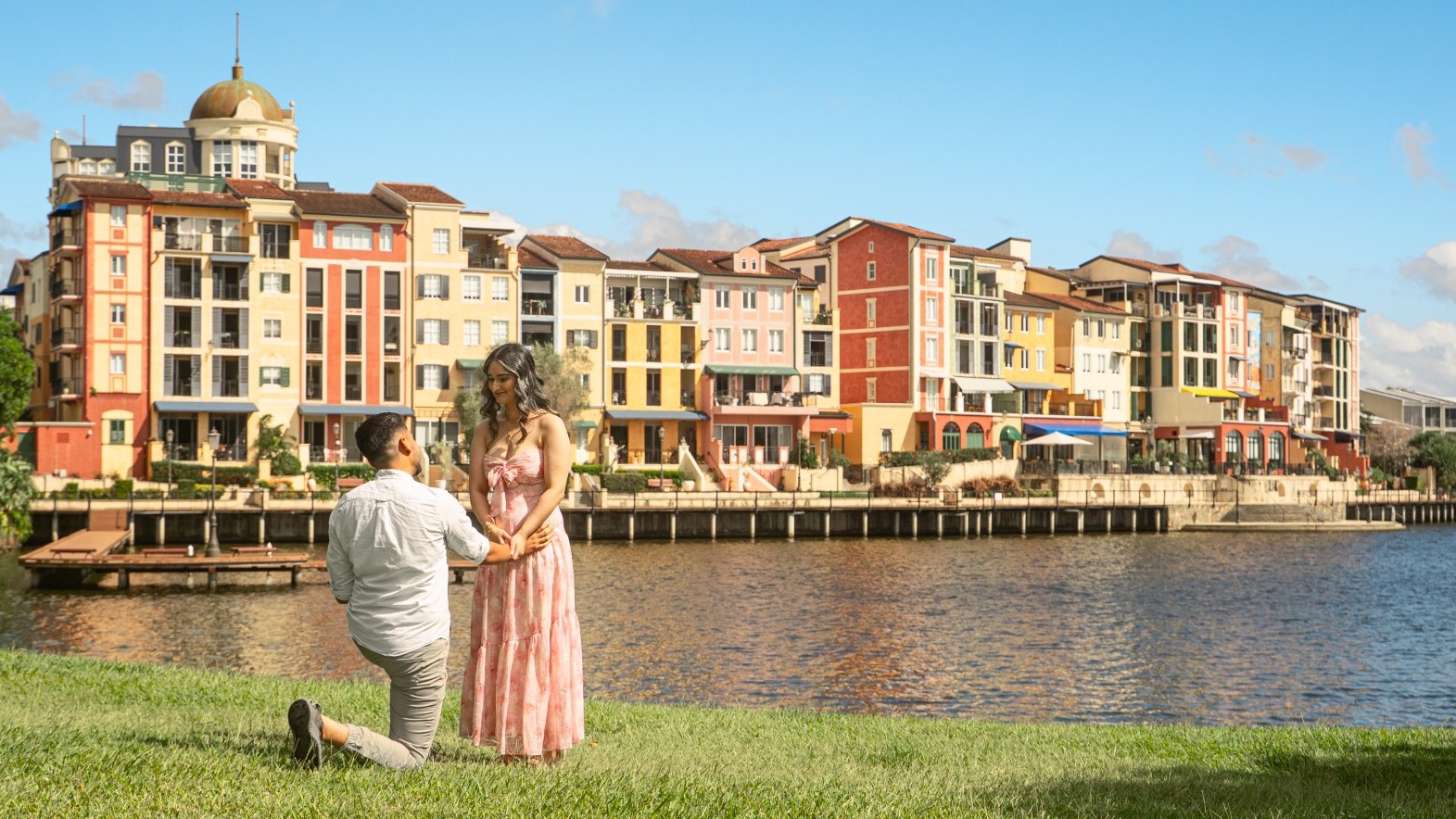 A person filming a traditional pink lion dance costume during an indoor event with seated guests.