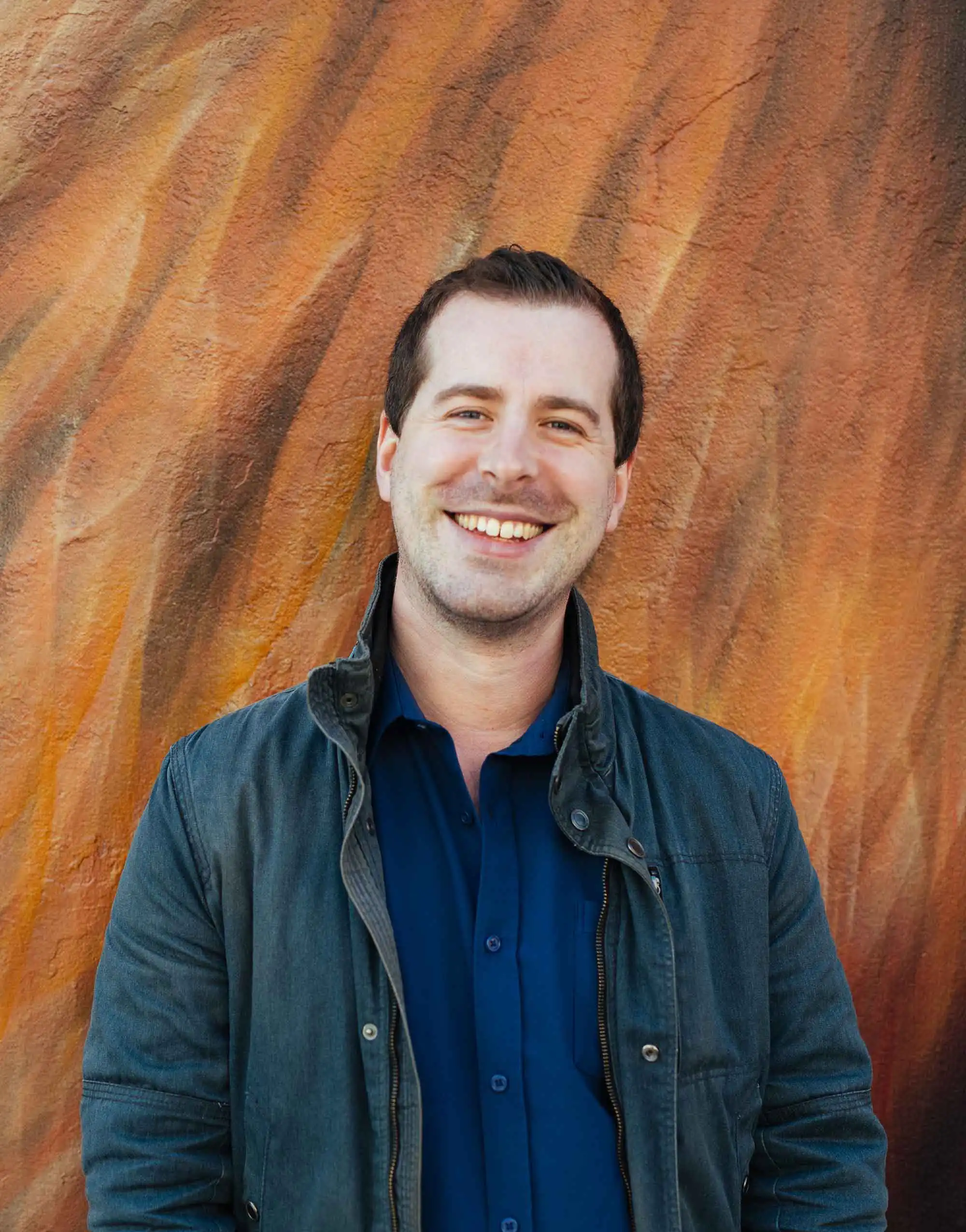 A photographic portrait of graphic and motion designer David MacKenzie against a painted background