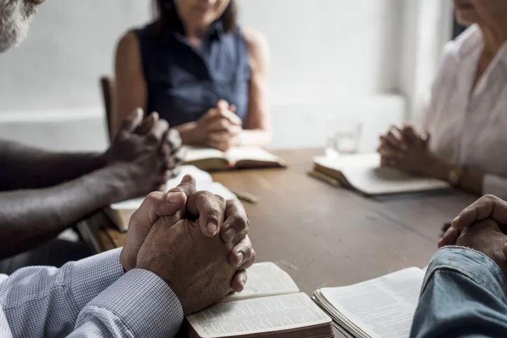 Gruppe i bønn og bibelsamtale rundt bord ved Evangeliesenterets Bibelskole