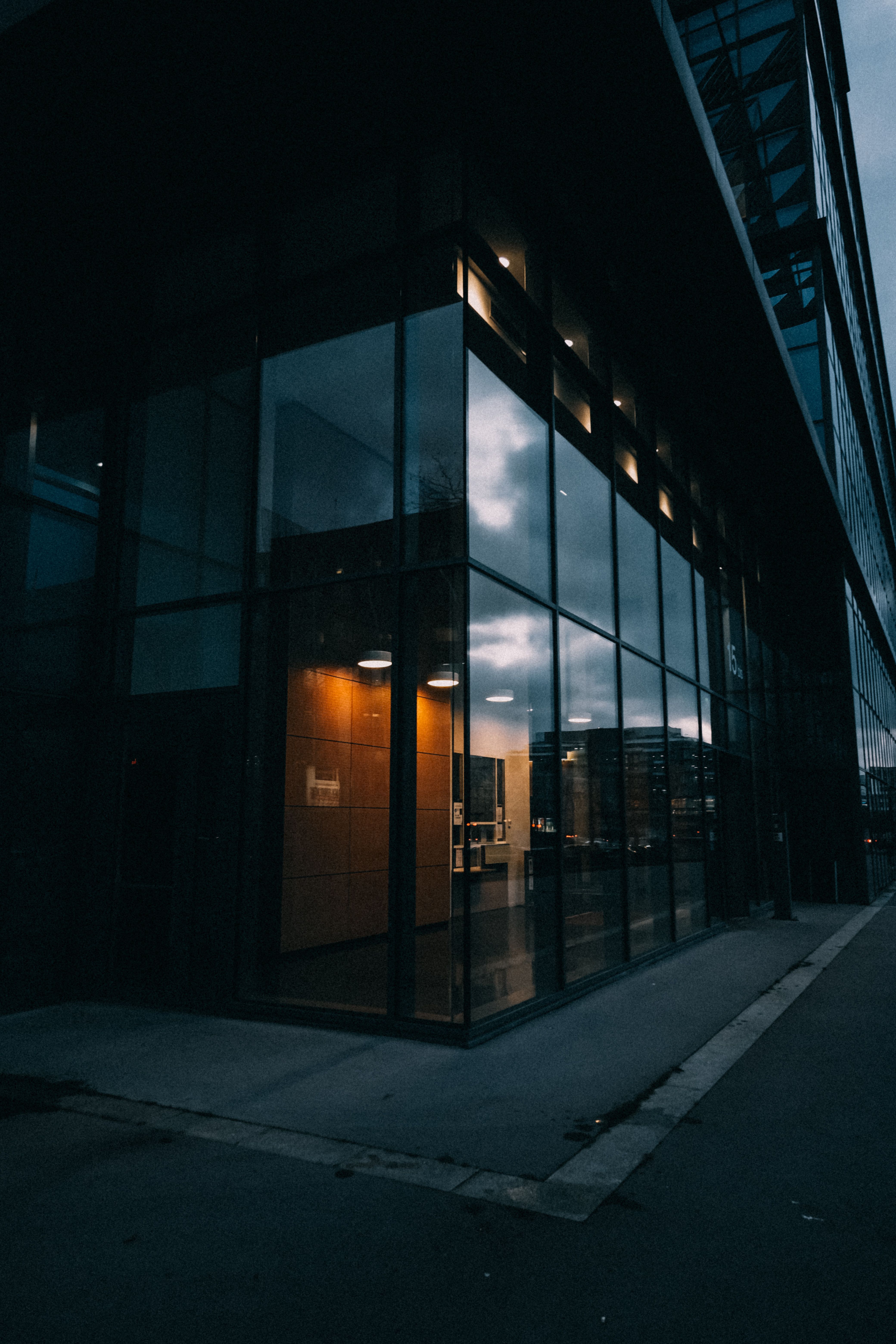 Sleek black car reflecting lights in a dimly lit modern showroom with glossy floor tiles.