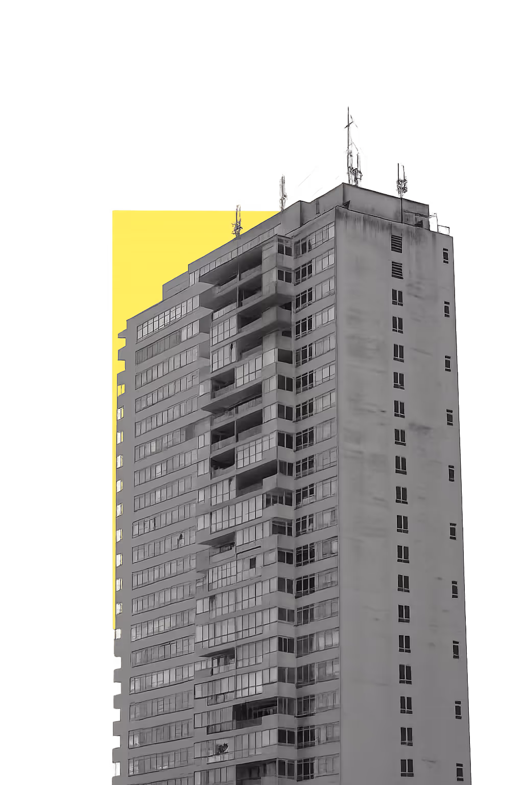 Tall gray building with antennas on top illuminated by a bright yellow light behind it.