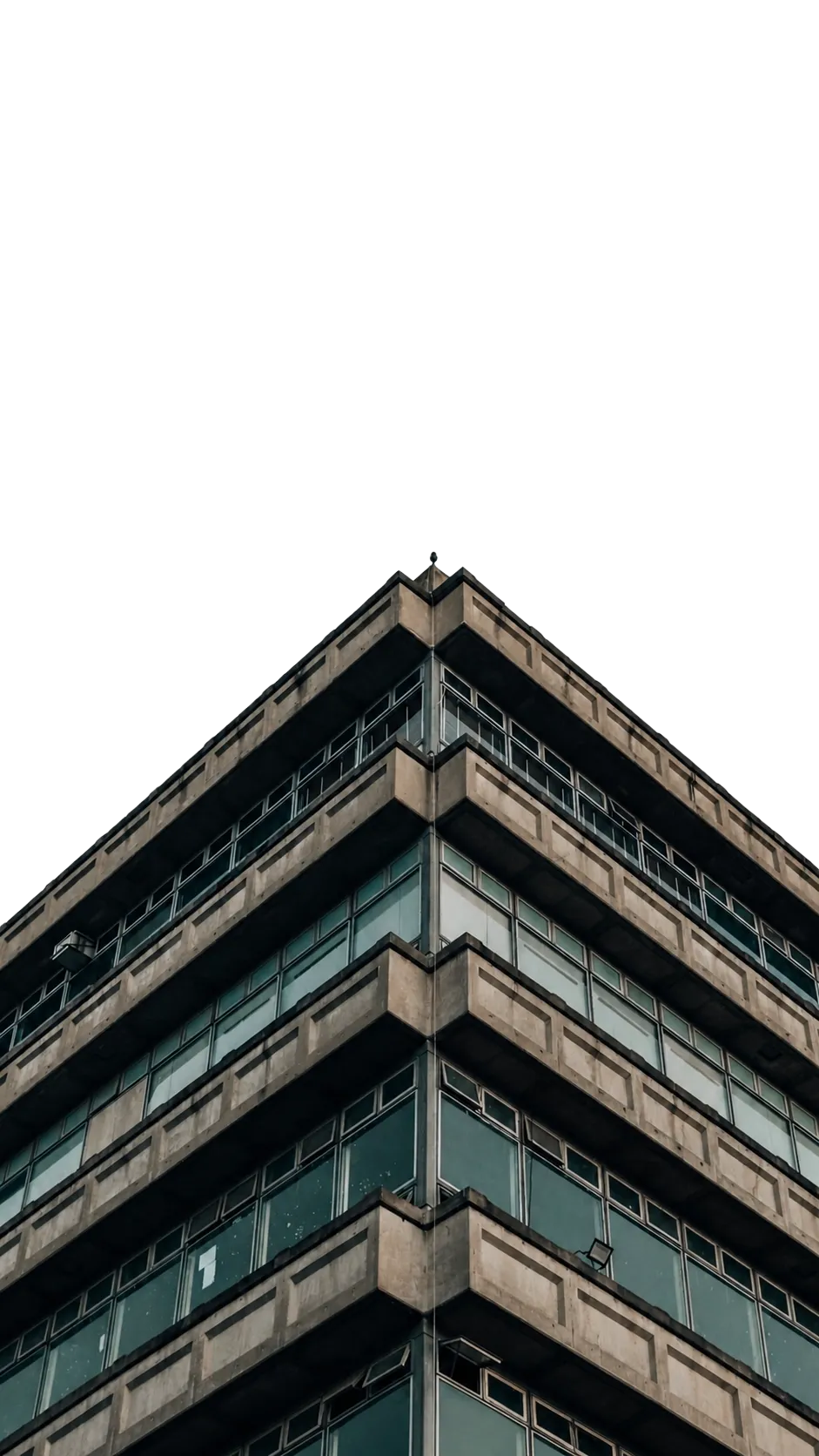 Upward view of a concrete and glass modern office building corner with overcast sky background.