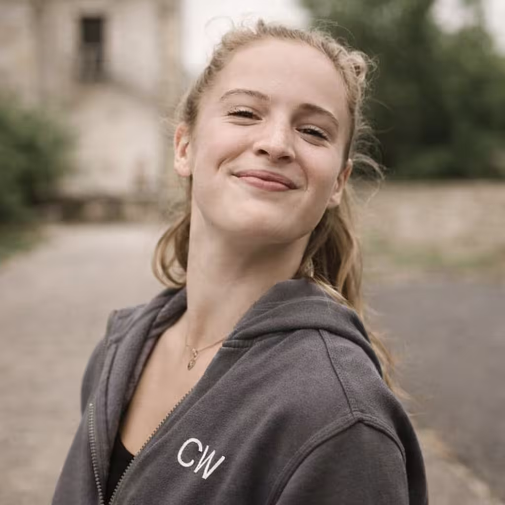 Middle-aged man with light beard and short hair wearing a white button-up shirt, standing outdoors with green foliage background.