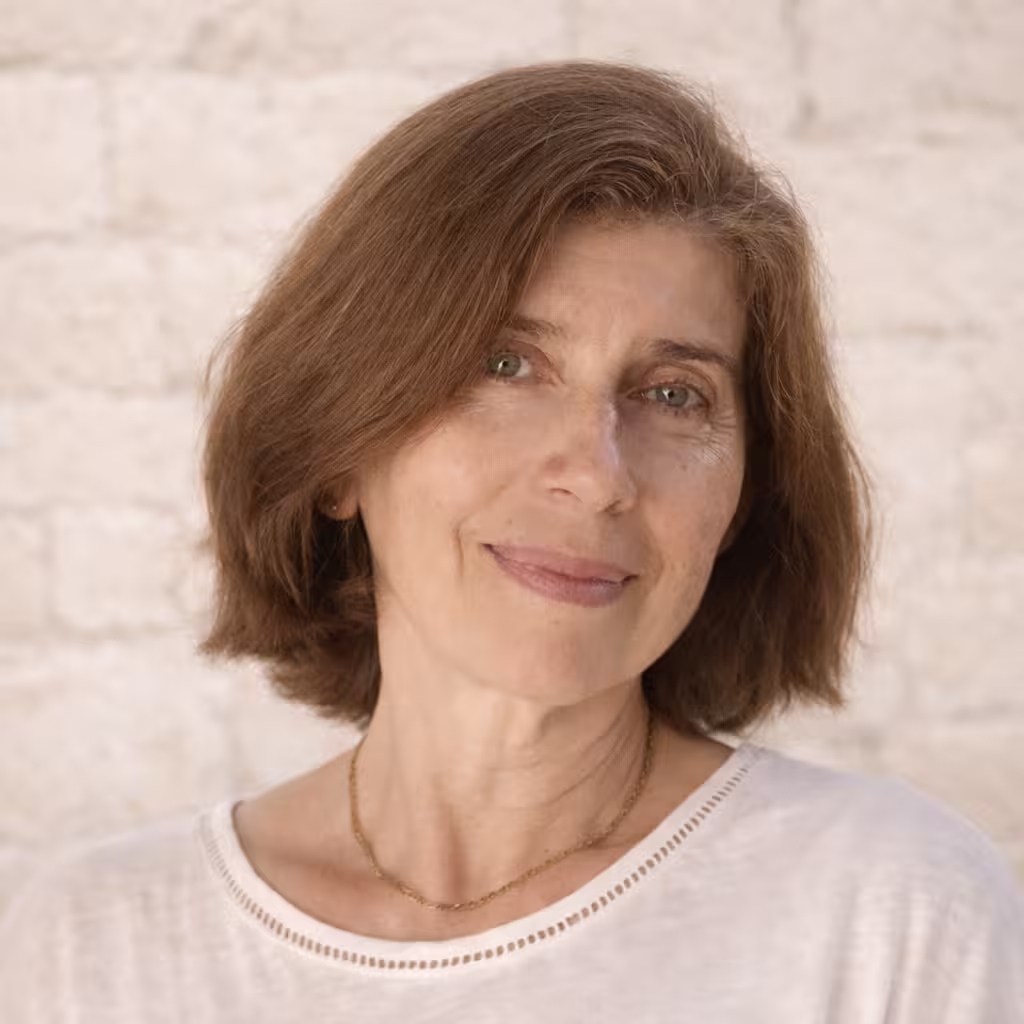 Middle-aged man with light beard and short hair wearing a white button-up shirt, standing outdoors with green foliage background.