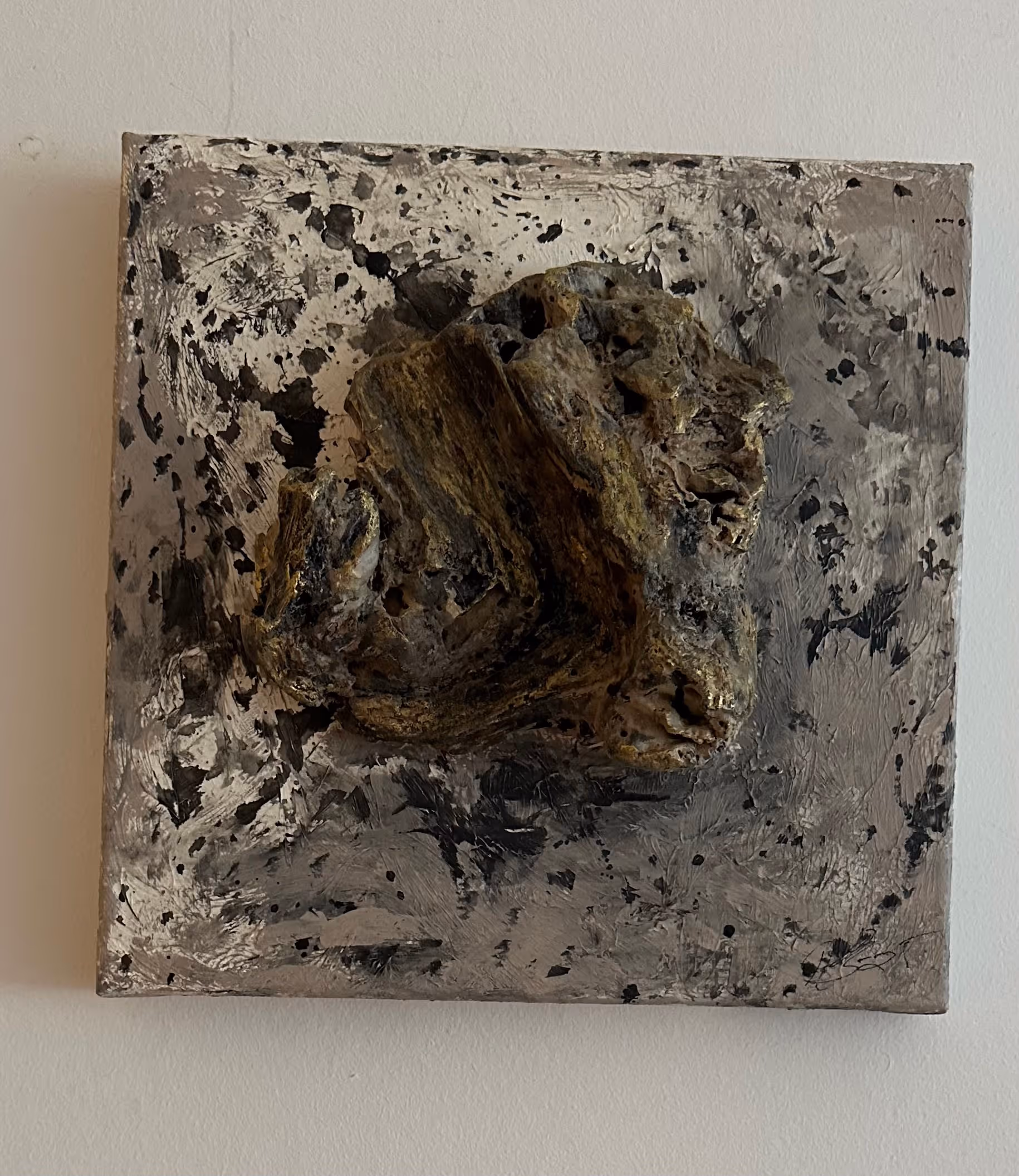 Abstract textured painting with a three-dimensional rough wood-like object mounted on a gray and black splattered canvas.