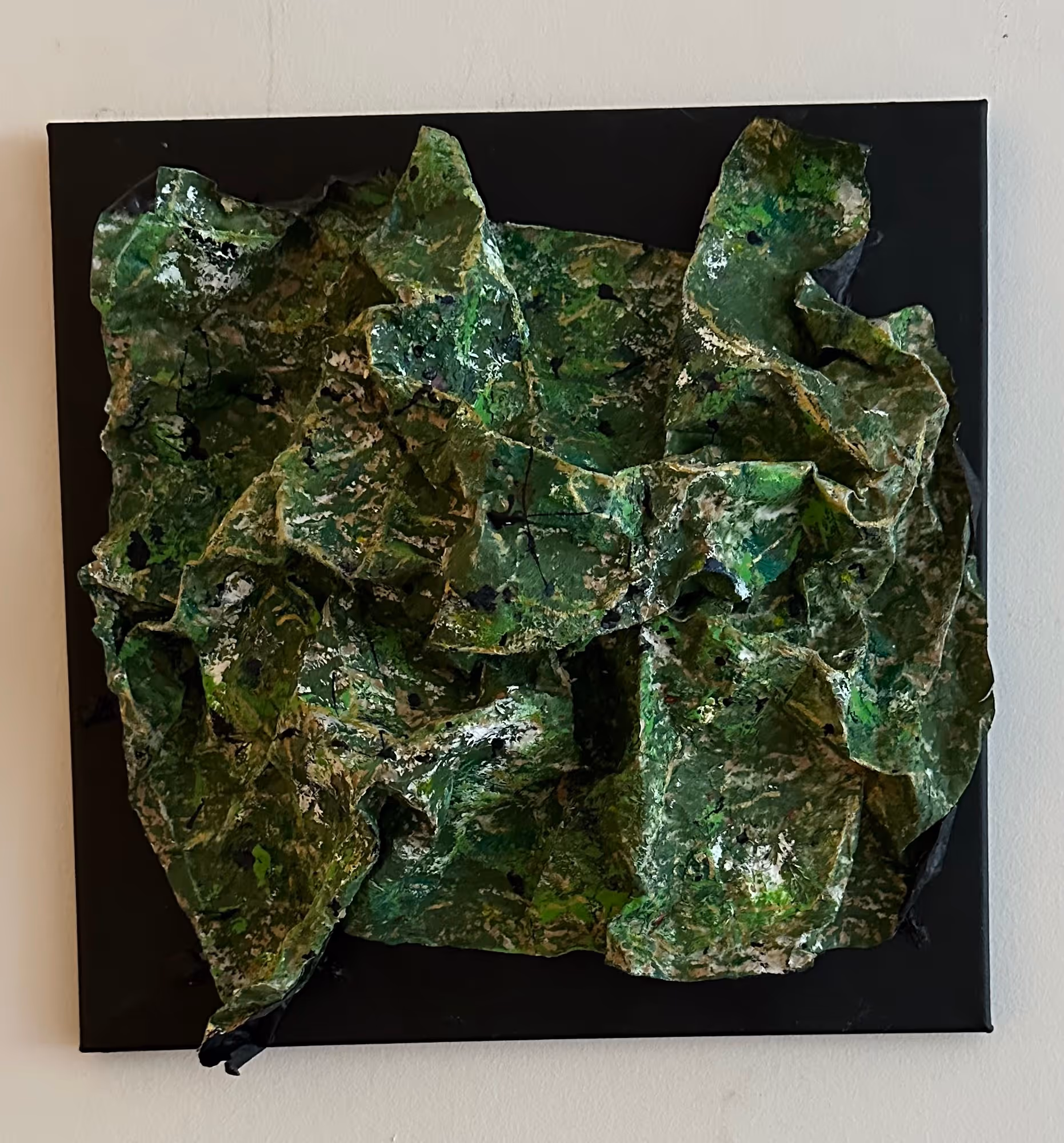 Abstract textured artwork featuring crumpled green, white, and black layers on a black square background.