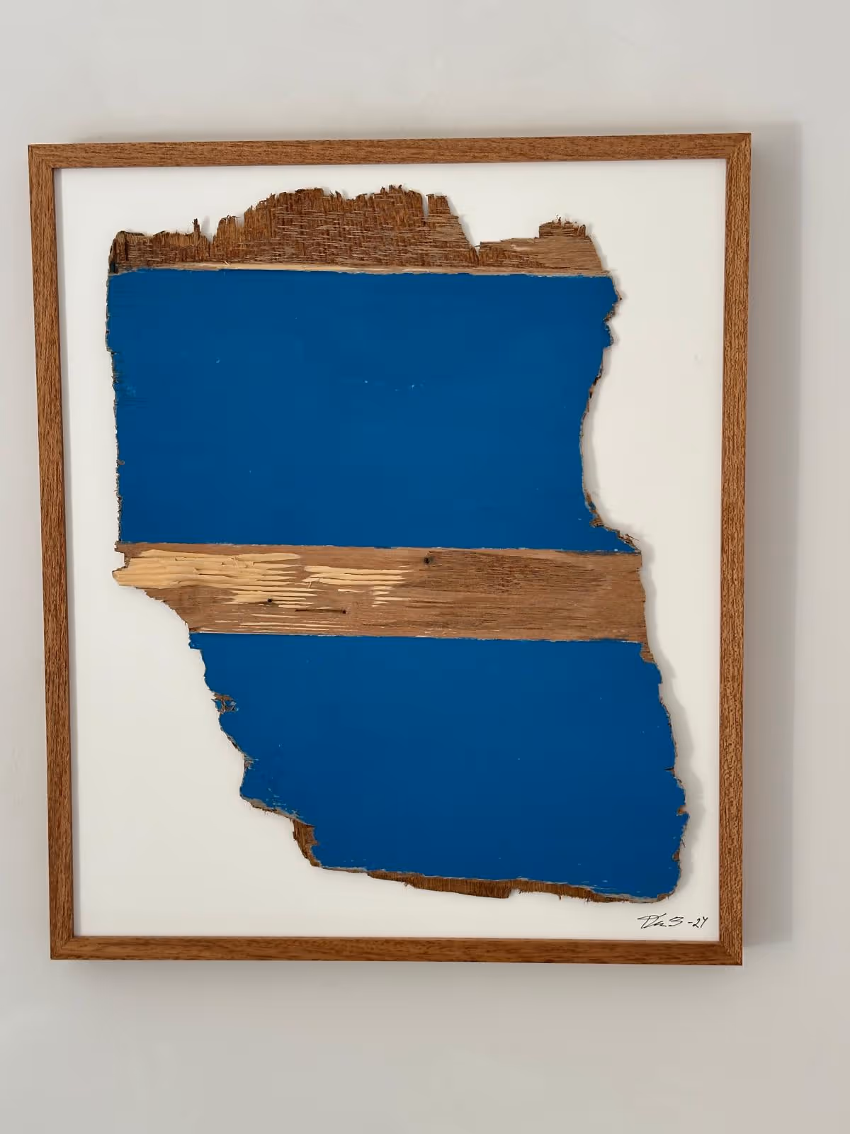 Framed artwork of a rough-edged wooden plank painted with two blue horizontal stripes separated by a natural wood stripe.