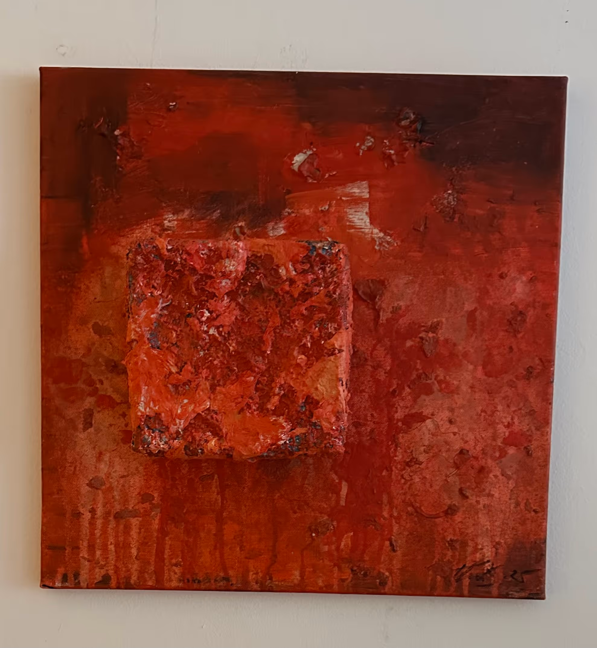 Abstract textured painting featuring various shades of red with a raised square in the center.