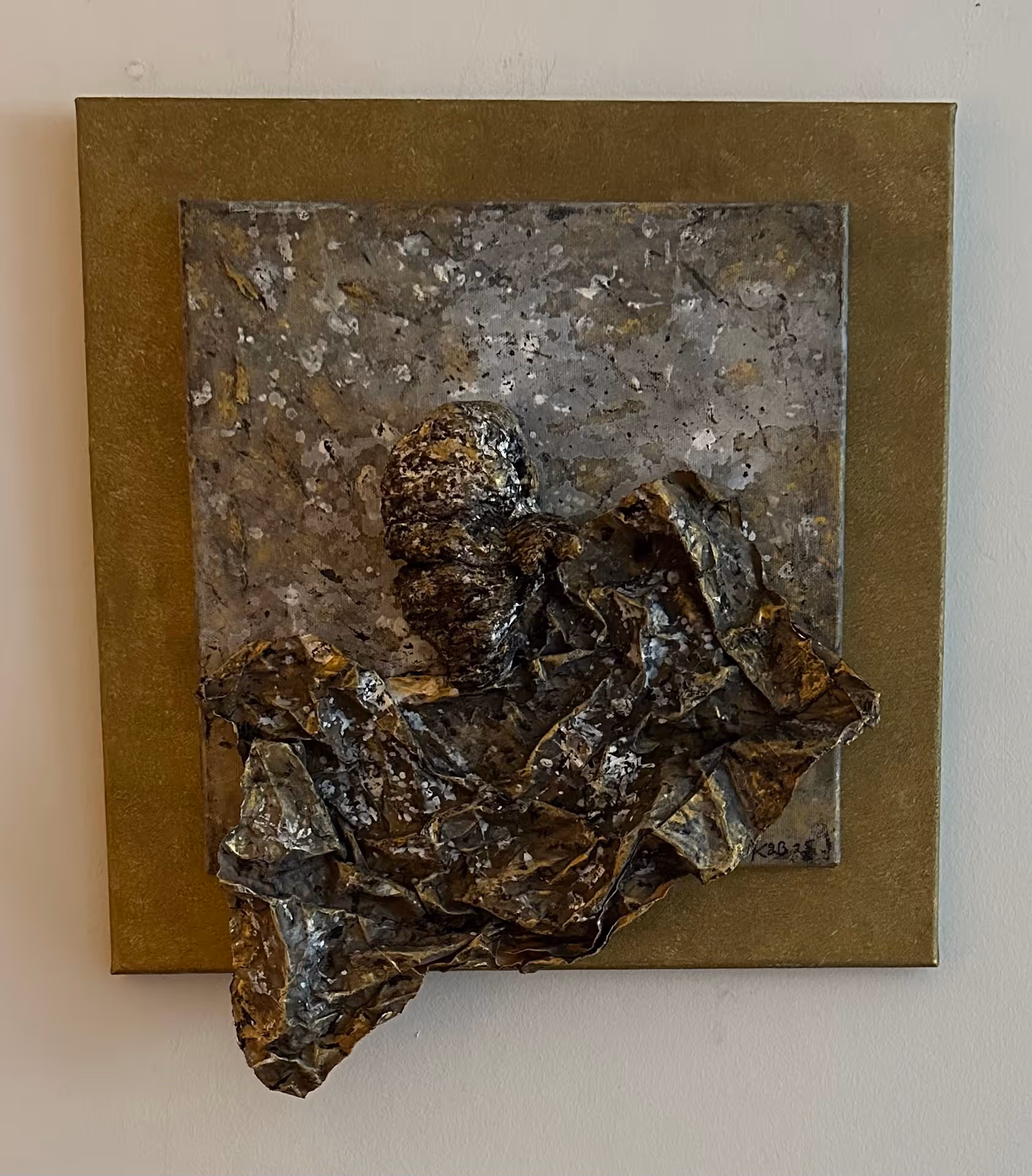 Abstract mixed-media wall art featuring a textured, raised human head and crumpled material on a square canvas with earth tones.